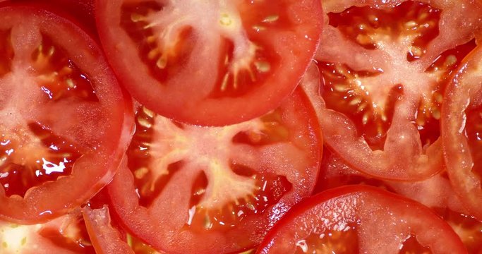 Slices of ripe tomato rotate slowly.