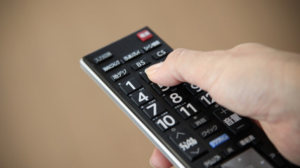 テレビのリモコンのボタンを押す指