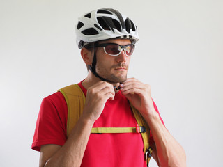 Portrait of bicycle courier, with yellow backpack. Man in helmet and glasses. White background..