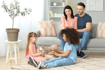 Happy couple with little adopted children at home