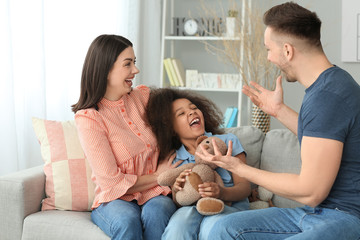 Happy couple with little adopted girl at home