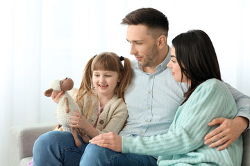 Happy couple with little adopted girl at home