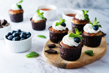 Chocolate cream cheese cupcakes with whipped cream, mint leaves and blueberry