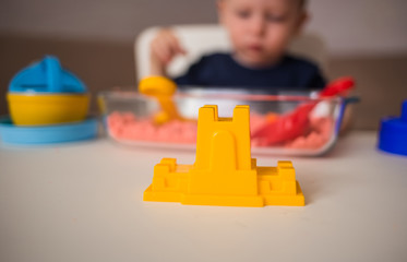 Yellow plastic fortress in the foreground. Games with sand at home.