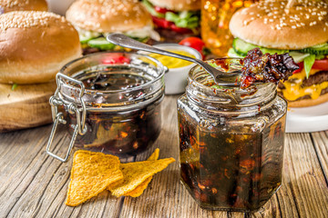 Homemade bacon jam in jars, with bread and burgers