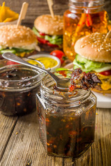 Homemade bacon jam in jars, with bread and burgers