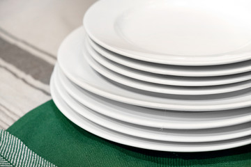 Plates white empty stack on kitchen table. Close up