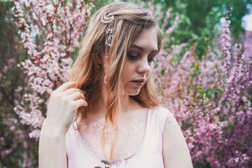 Girl in a delicate dress with mehendi on the body, in flowering almonds