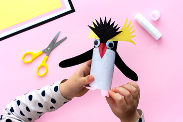 Making a penguin from colored paper and a roll of toilet paper. Children's art project. Step by...