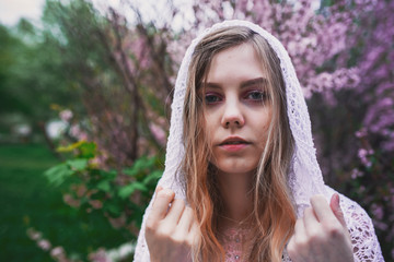 Girl in a delicate dress with mehendi on the body, in flowering almonds