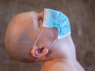 Fototapeta premium attractive girl with shaved bald head in medical mask with bare shoulders. Beautiful middle age woman cancer patient without hair