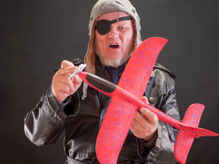 portrait of a bizarre elderly man has in his hands red airplane and propeller spinner torque. fancy...