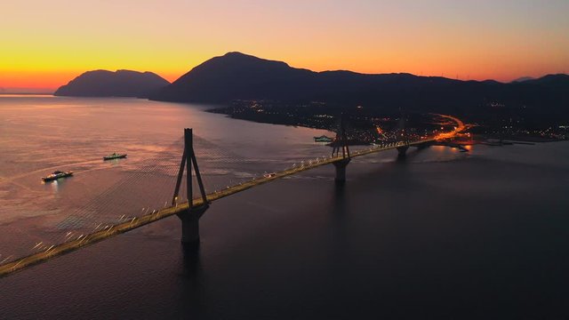 Sunset of rio antirrio bridge with illuminated and car traffic,peloponesse,Greece