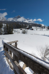 Fototapeta na wymiar Wooden Fence and Snow-covered Firs in a Snowy Mountain Panorama