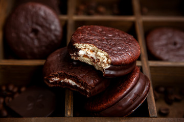 A few sweet Choco pie desserts on a wooden background among scattered coffee beans.