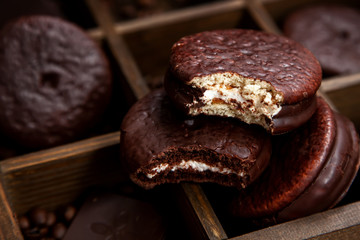A few sweet Choco pie desserts on a wooden background among scattered coffee beans.