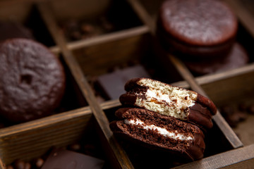 A few sweet Choco pie desserts on a wooden background among scattered coffee beans.