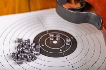 White shooting target and shotgun for pneumatic weapons. Shooting accessories on a wooden table.