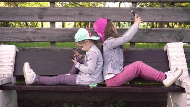 Two little girls make selphy and  play mobile games, sisters are watching on the smartphone screen, kids are playing online