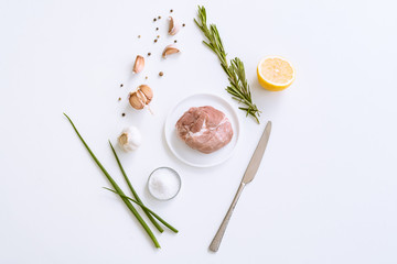 The concept of cooking meat with spices. Raw pork meat, onion, rosemary, garlic, chili pepper on a light background top view.