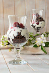 Layered dessert with chocolate cake, whipped cream and raspberry in a jar, spring flower decoration