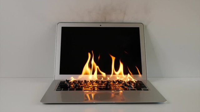 Overheating laptop bursts into flames.  Damaged technology that is irreparable.  Apple macbook air catches on fire and burns in slow motion.