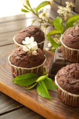 Chocolate muffin on rustic dark wooden background with flowers of cherry