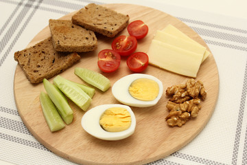 boiled egg, cut in half, cucumber wedges, cheese wedges, toast, healthy food on a breakfast board
