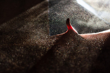 beautiful set of dust particles and thumb against the background of rays of light in a dark room