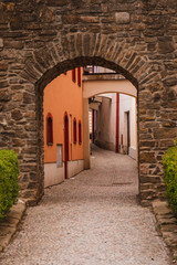 Beautiful stone gate near the medieval town with a winding alley and colorful houses