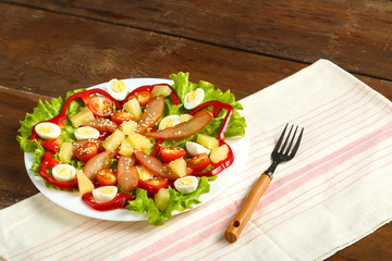 Pan-Asian salad with chicken and pineapple in a plate on a wooden table on a napkin.