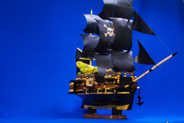 Wooden model of a handmade pirate warship on which a parrot sits.