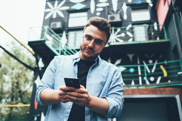 Confident young man messaging on smartphone in street