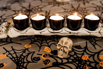 A bone with tea lights on it, skulls in the foreground and Halloween trim