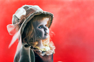 Profile portrait of beautiful porcelain vintage doll wears a headdress with blond curly hairs and...
