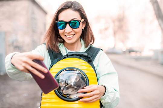 Happy Girl Pet Owner Smiles In The Park Walking With Her Cat. She Taking Selfie Photo For Her Blog Or Social Media. Friendship And Cat Carrier Concept