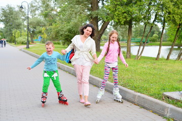 Sports family-mother with children on roller skates in the Park