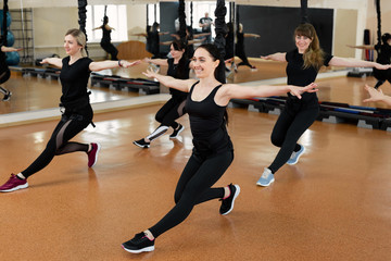 Group of active sports girls in black sportswear are engaged in budgie fitness in the gym. Bungee...