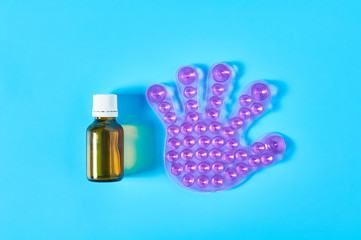 One rubber toy human palm with many suction cups near full bottle of medicines on blue background. Healthcare concept