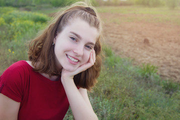 Fototapeta premium Beautiful young teen girl smiling in a field outdoors. Copyspace.