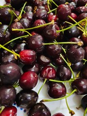 Close up of dark cherries with stems. Cherries contain antioxidants and anti-inflammatory compounds that strengthen the immune system. Therefore, cherries should be used in COVID 19 pandemic