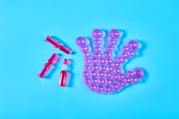One rubber toy human palm with many suction cups near red vaccine on blue background. Healthcare concept