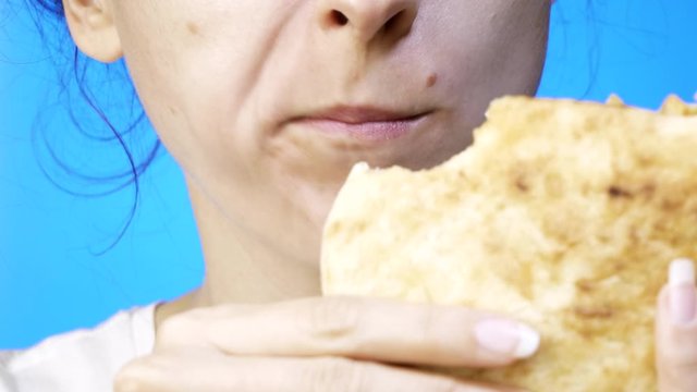 closeup of woman eating, biting pita. isolated on blue background