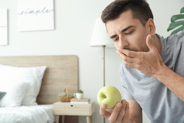 Young man suffering from anorexia with apple at home