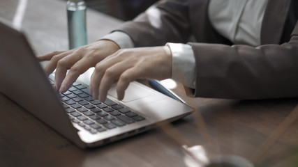 Hands of businesswoman typing on a computer keyboard. Woman at workplace with antiseptic spray and incense sticks on it