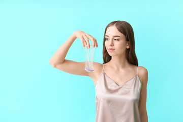 Young woman with female condom on color background