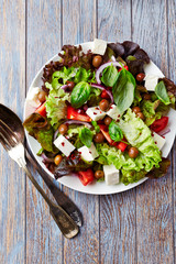 Healthy salad with feta cheese, olives, red onion and tomatoes. Rustic wooden background. Top view. Copy space.	