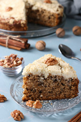 Homemade crumb cake with walnuts and cinnamon in plate on light blue background, ready to eat, closeup, Vertical format
