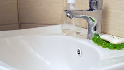 White washbasin and water tap. Metal economical water faucet and white ceramic washbasin in modern bathroom. Hygiene concept