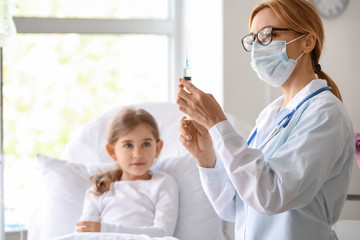 Female doctor working with little girl in hospital room